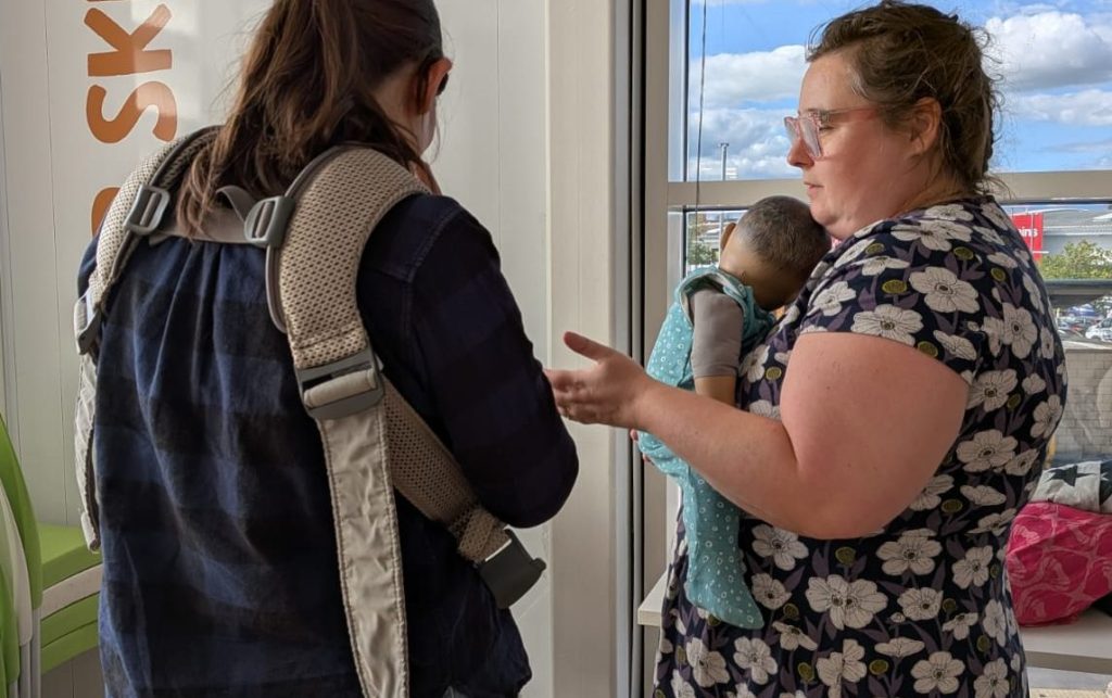 Fit check. Baby Carrying Peer Supporter helps parent to get a good fit with their own baby carrier. At Fratton Sling Library.